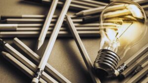 Glowing lightbulb among pencils symbolizing creative unique content ideas for SEO content marketing strategy
